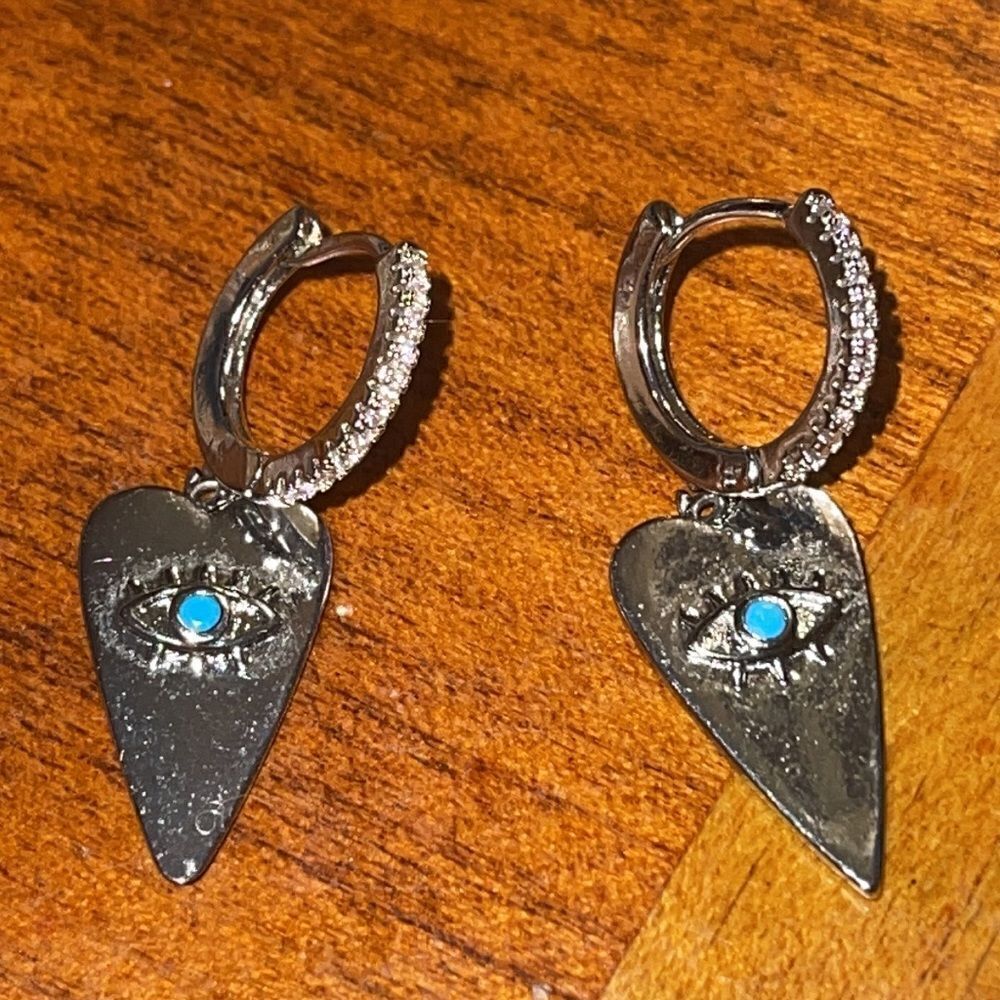 Silver tone heart shaped dangle earrings with evil eye